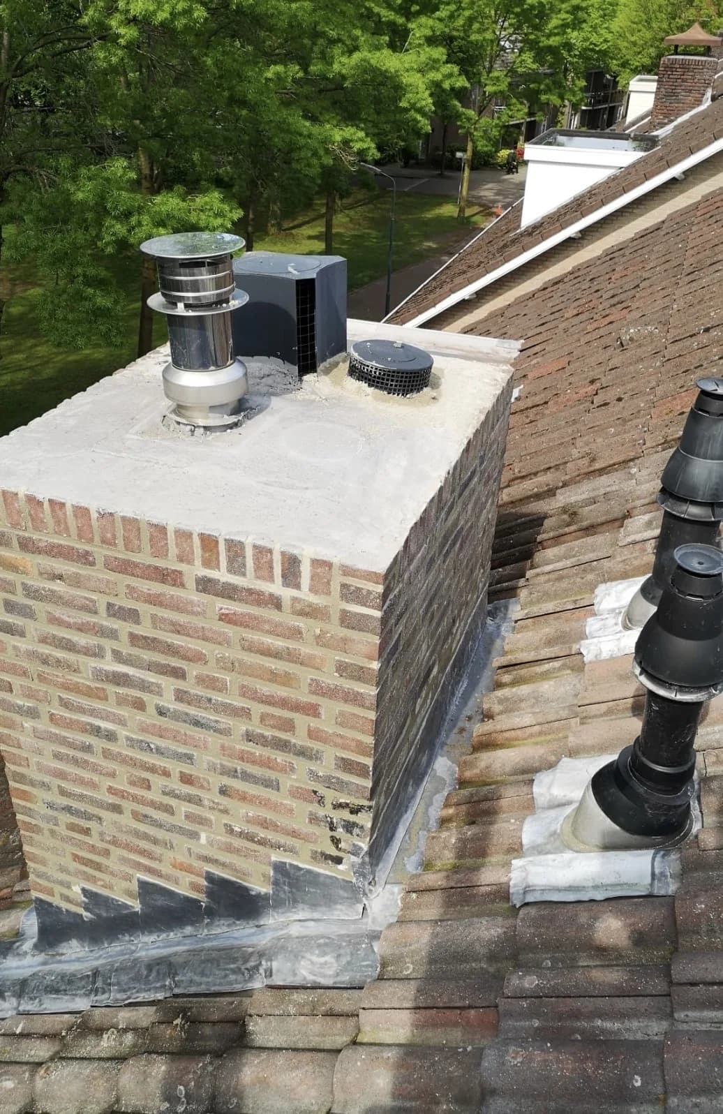 Gerenoveerde schoorsteen met nieuwe betonnen kop, rookgasafvoer en nieuw loodwerk