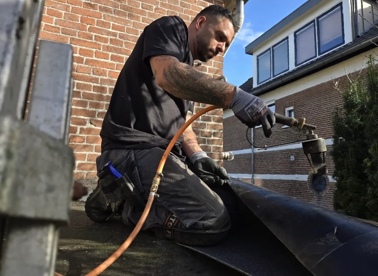 Raymond Hoonhorst brandt bitumen op een plat dak
